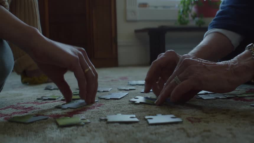 Two people are solving a puzzle indoors together