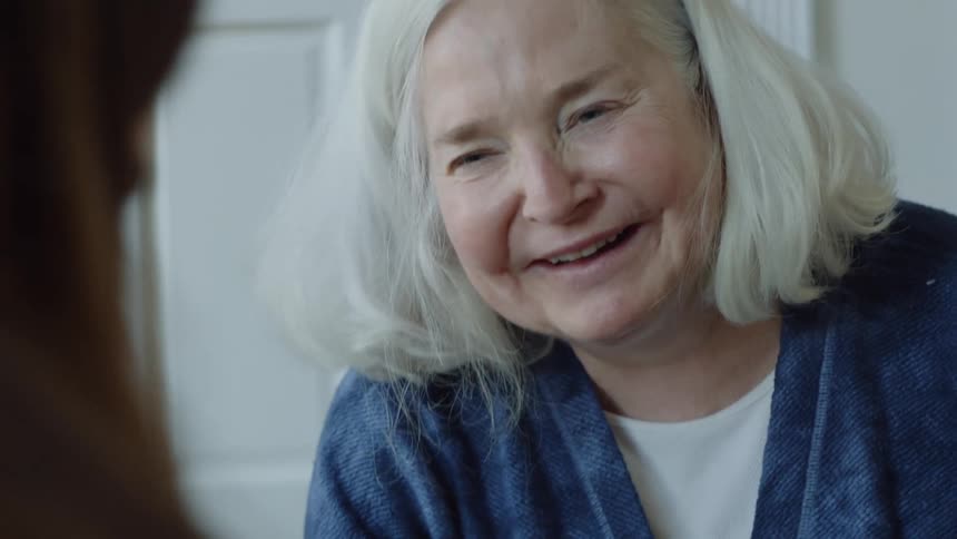 Elderly woman smiles at young woman playing card