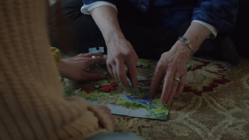 Mother and daughter assembling a puzzle over the rug in the living room