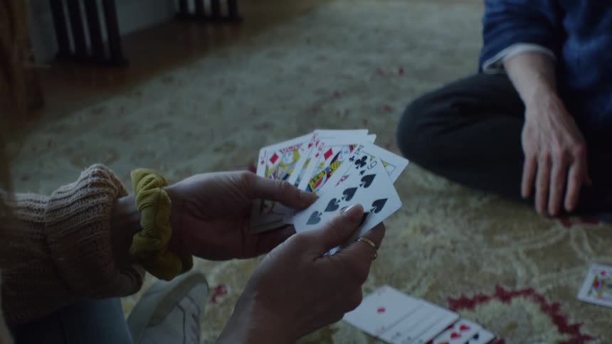 Two people are sitting on the ground and playing a card game