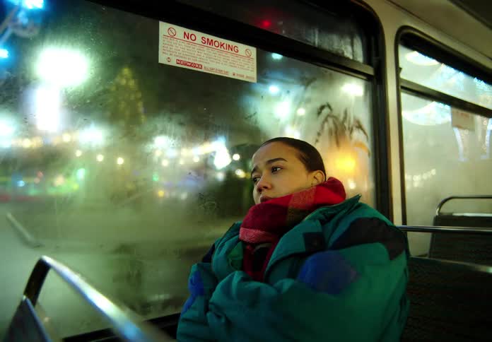 Woman with coat and red shawl travels on bus in the city at night