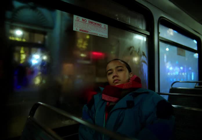 Woman with red scarf and blue jacket travels on bus at night