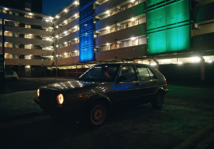 A man is sitting in a parked car in an empty lot