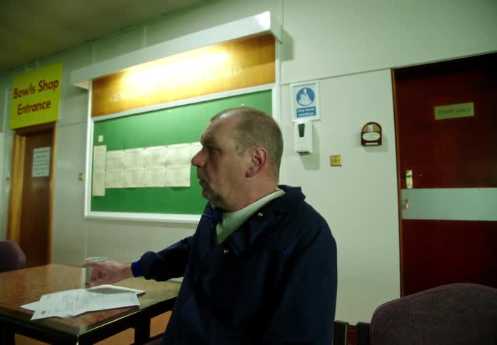 Man sitting on a chair in a large meeting hall gets sad after receiving bad news