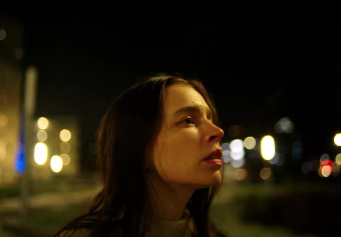 Close up of a young sad woman dancing in the city streets at night