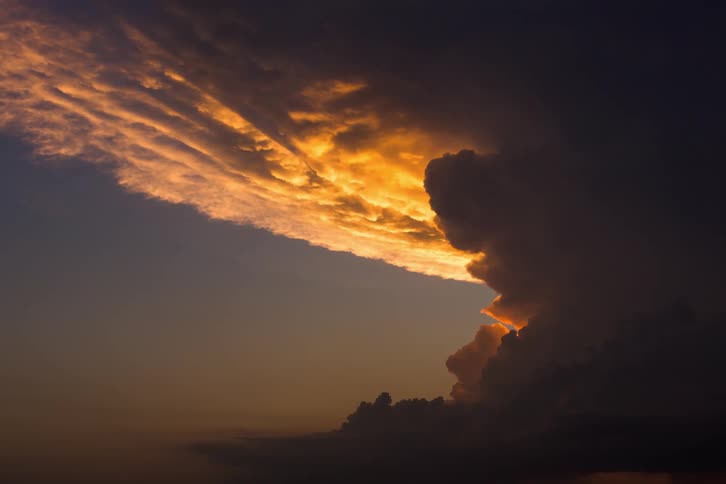 The sun setting behind billowing clouds