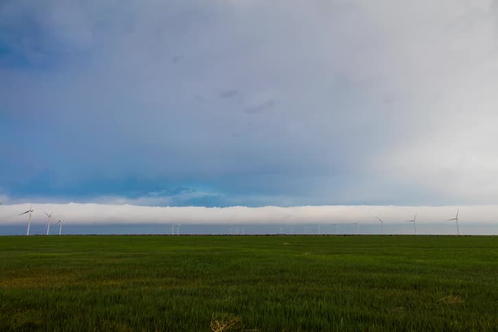 Clouds pass over a field with wind turbines