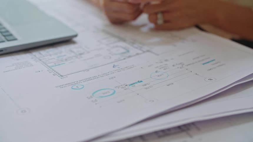 A close up of a womans hands as she uses a marker to make a circle on papers