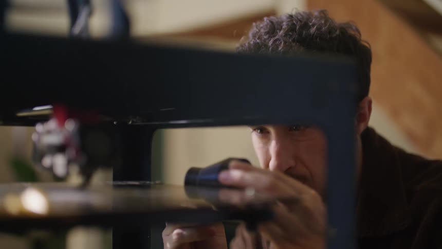 A young man is indoors and fixing something inside of his house