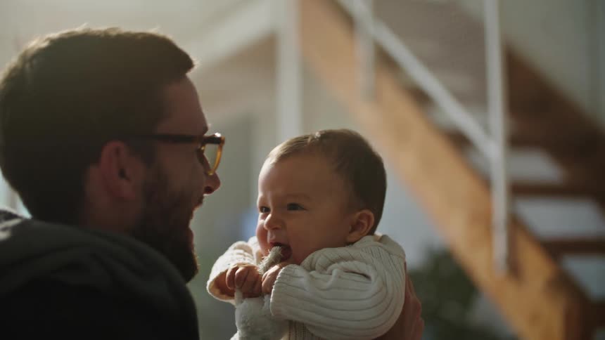 A man is playing with his baby and lifting him into the air