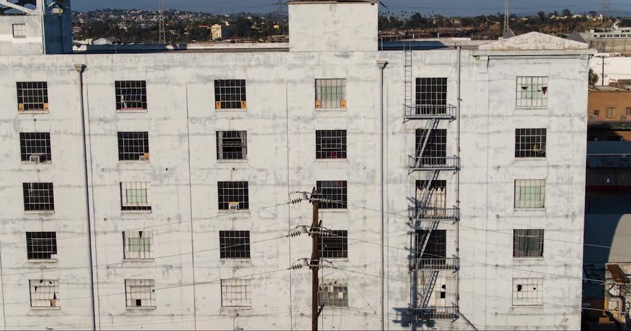 An aerial view of an wornout industrial building in front of an urban city skyline