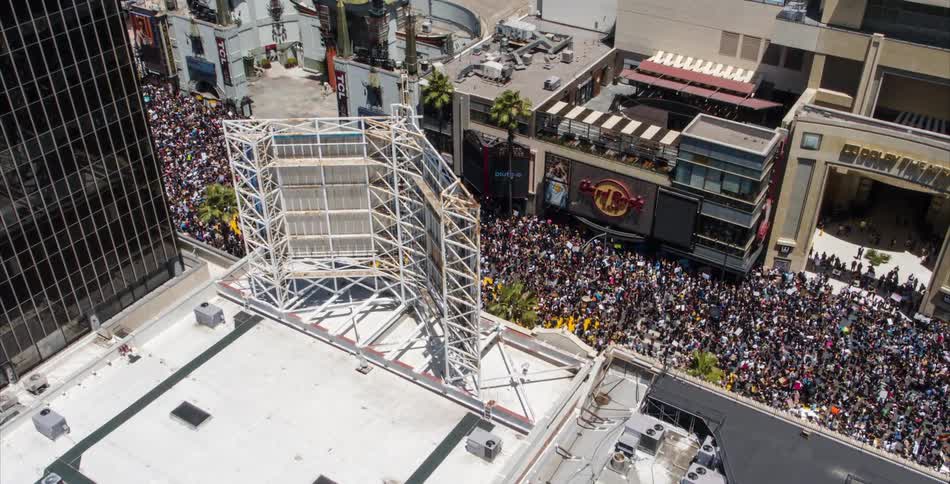 A large crowd is walking through a downtown city