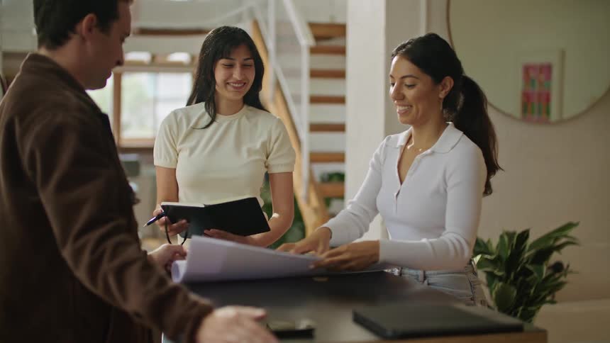 Three friends are discussing something while standing in a house