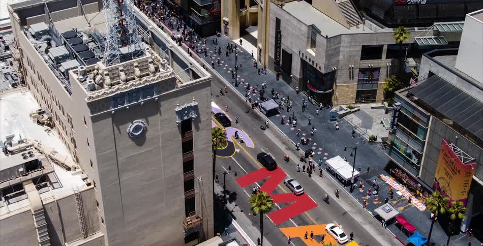 An aerial of a city street with many people crowded walking on the street between buildings