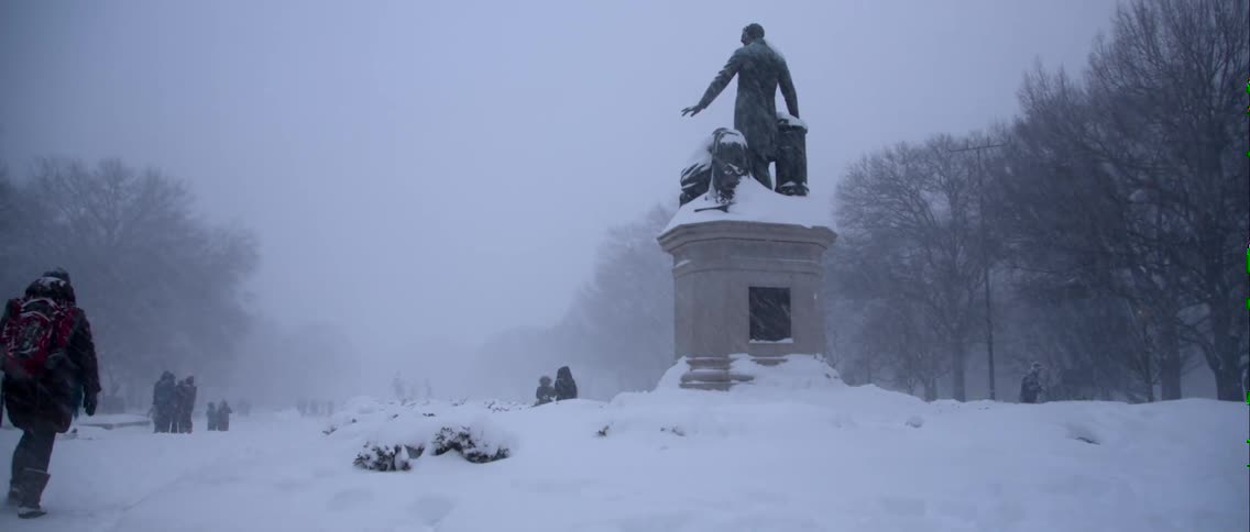 People walking near a statue on a very snowy day