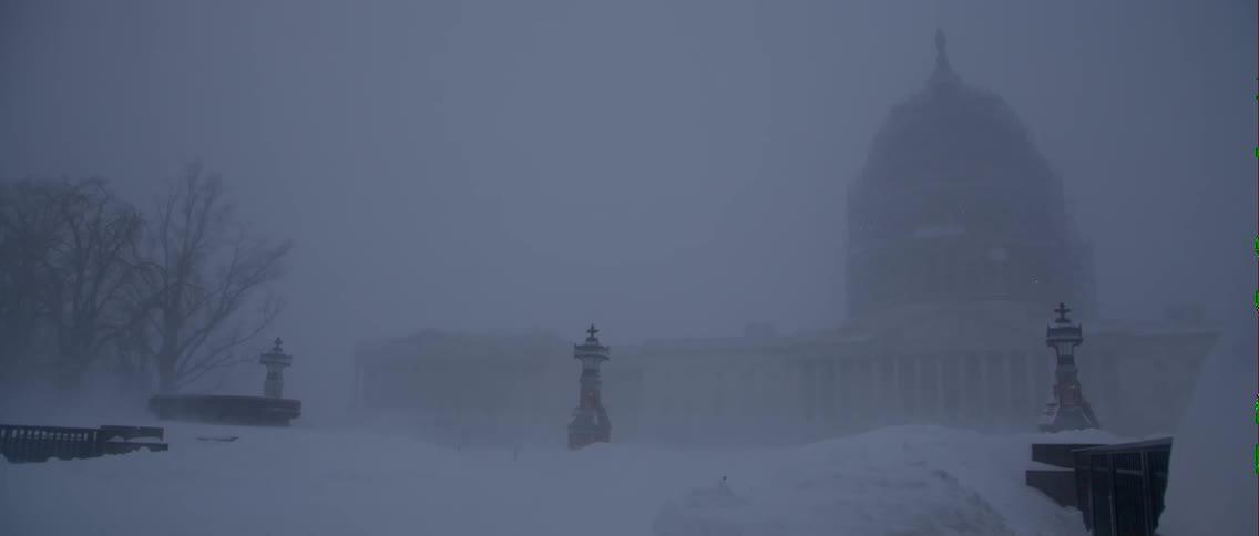 Statues standing in the snow before a majestic building on a snowy, cloudy day