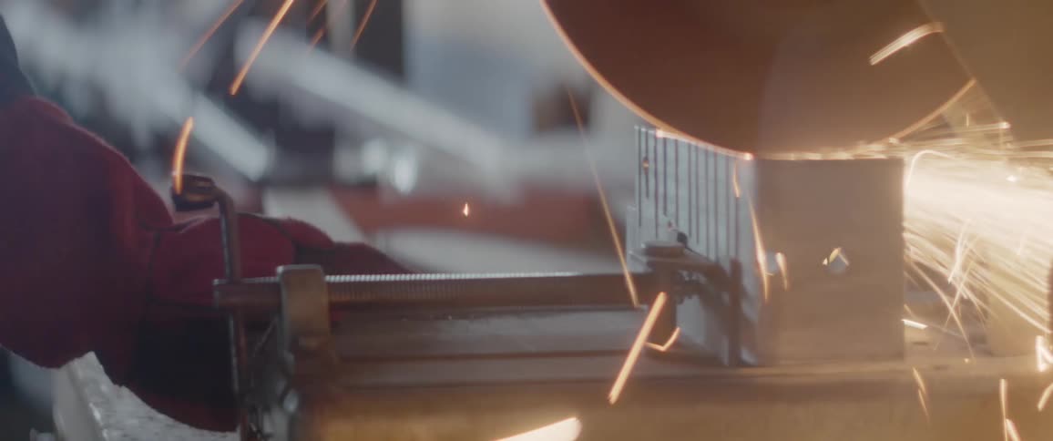 A man cuts into a piece of steel with a chop saw