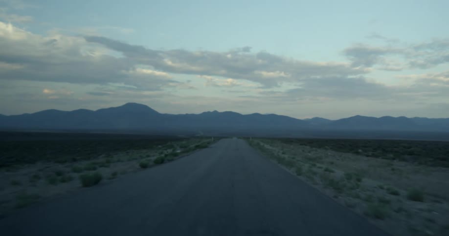 Traveling down desolate highway towards mountains