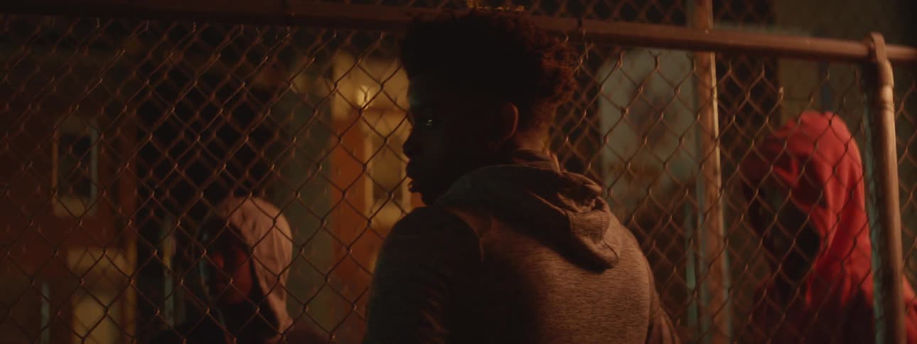 A man talks through a fence at night