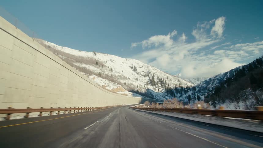 A drone view of a highway through the snowy mountains