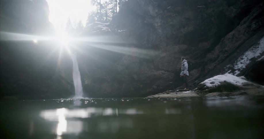 A man is standing by a water fall and river