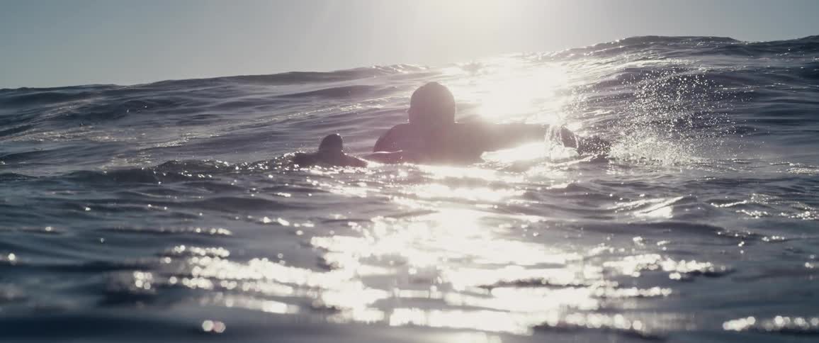 A man swims on his surfboard in the ocean
