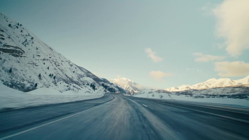 A time lapse of a highway traveling through snow covered mountains