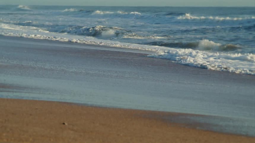 Ocean waves washing ashore a sandy beach
