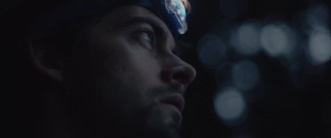 Man with head light looks up
