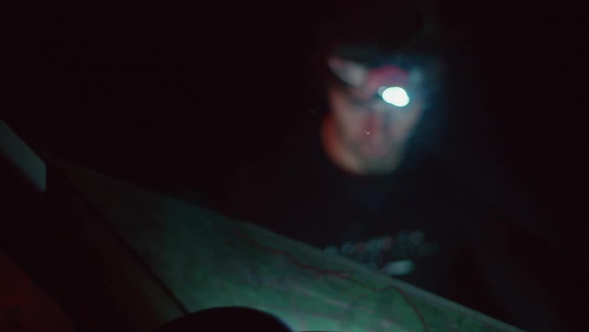 A man is reading a map while standing outdoors at night