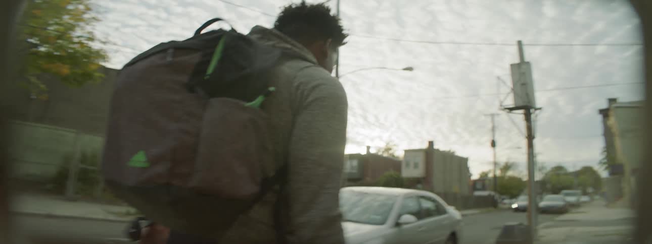 A man walks down a street dribbling a basketball