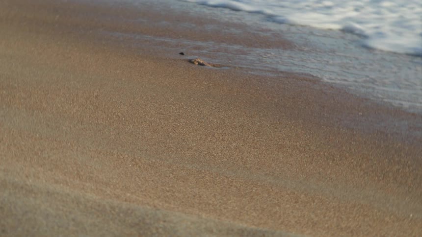 Close up of small waves gently crashing on the coast at daytime