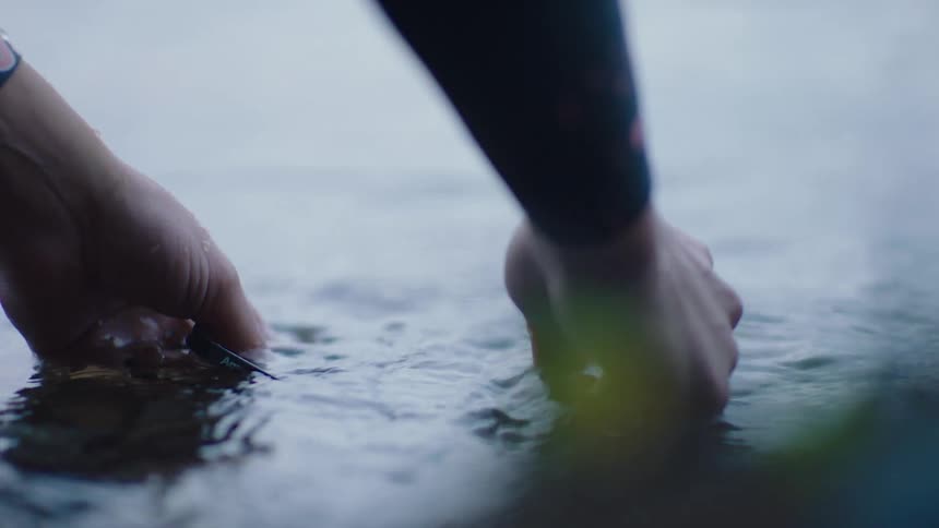 A close up of a persons hands as they submerge swimming goggles into water