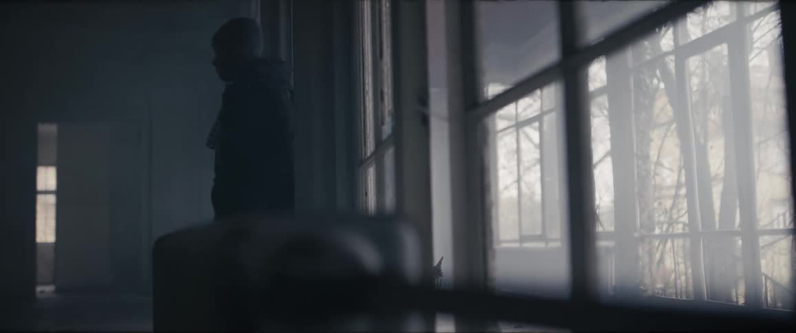 A young man is walking inside of a house in the day time