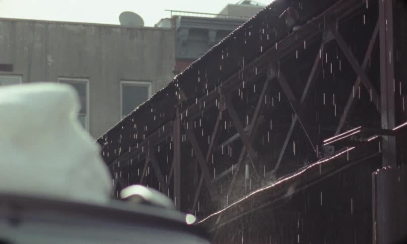 Melting snow falls along a fence behind a building