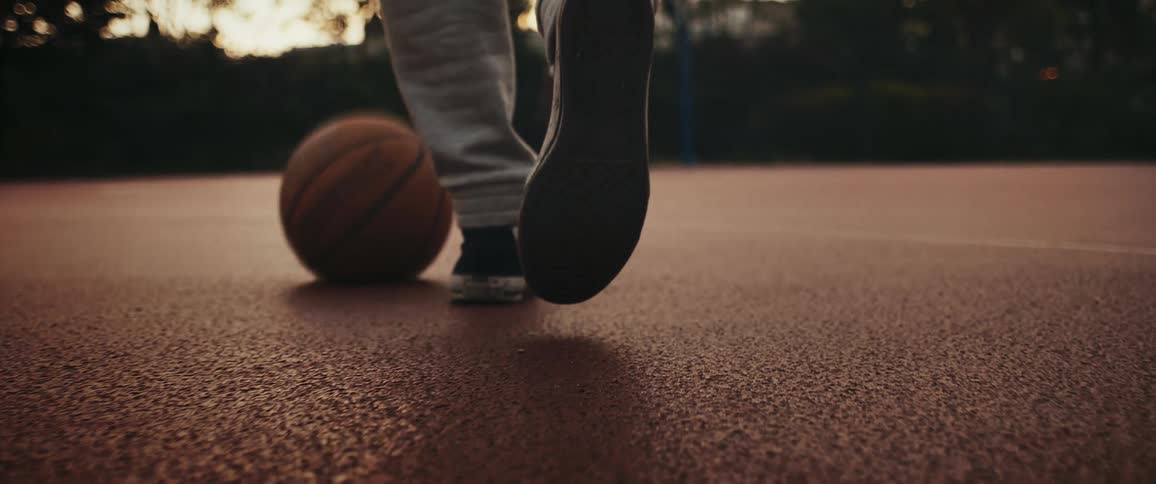 A person is dribbling a basketball on concrete