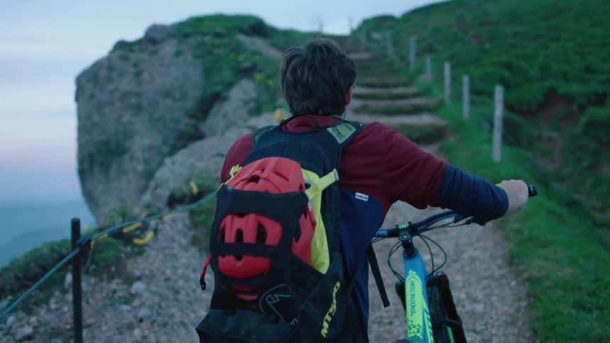 A male is biking up a mountain during spring