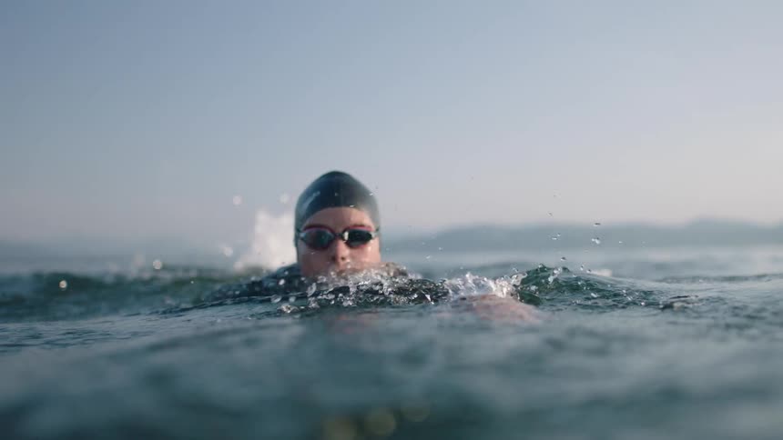 A young woman is swimming outside in the day time