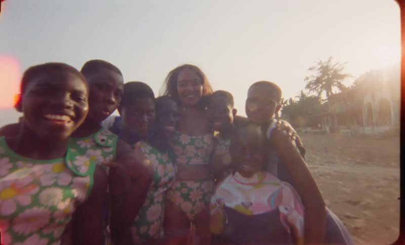 A group of young black girls smile for a photo on the beach during the day