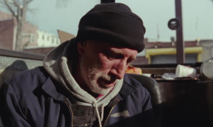 Close up of the face of a sad elderly man sitting near a window crying while talking