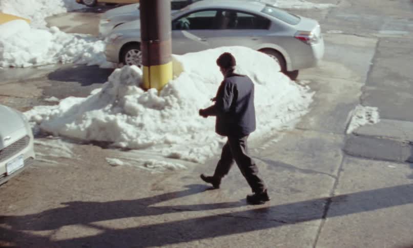 Man changes vehicles on a parking lot at winter caught on vintage film