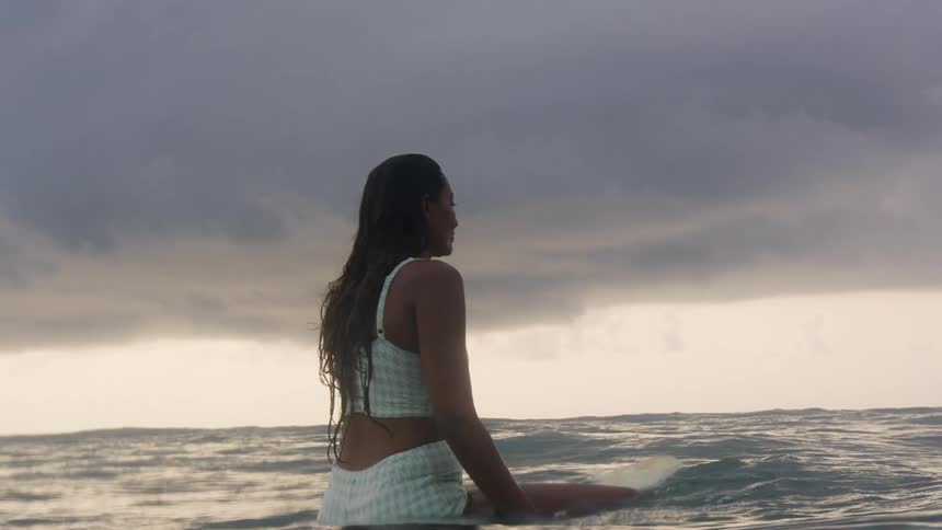 A woman is sitting on a surfboard in the middle of the ocean