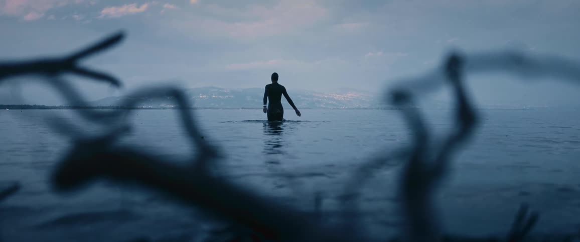 A person is swimming in ocean water at dusk