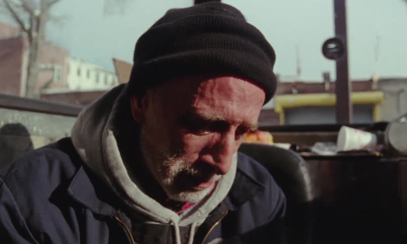 Elderly man cries and wipes snot near window showing buildings