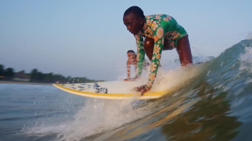 Two females are surfing on ocean water during dusk