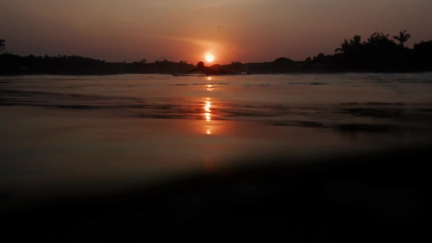 A person is swimming in water at dusk