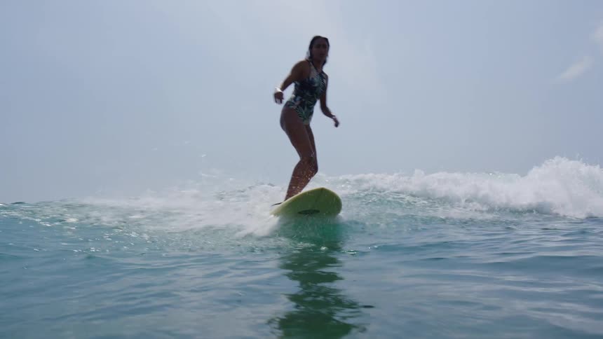 A woman is surfing on ocean water during midday
