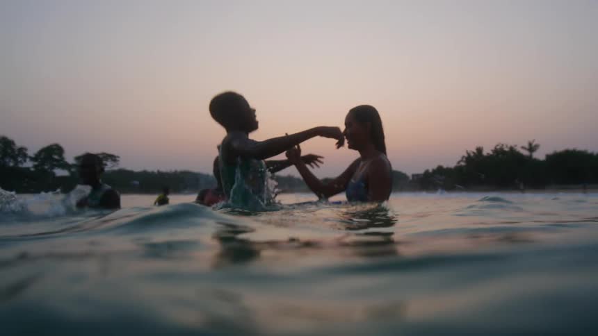 A group of friends are swimming together at dusk