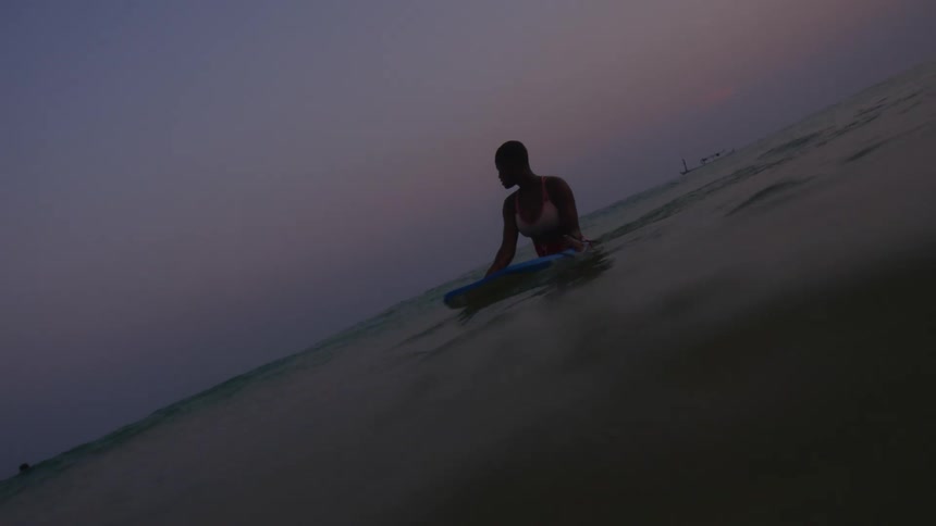 A teenage girl is in the water swimming with a shortboard