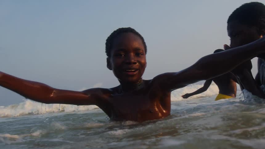 Youths play in water near beach as foaming waves roll toward them